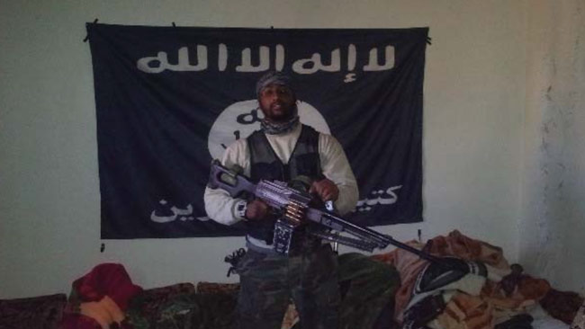 Al Amin Sultan poserar framför en islamistflagga. Foto: Polisen