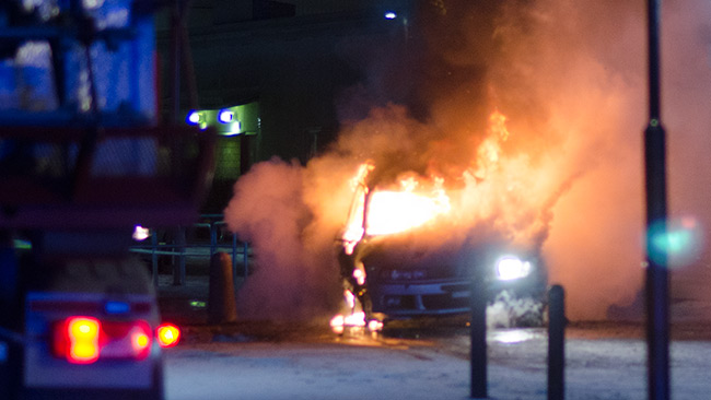 Här brinner bilen intill en stor byggnad i Norsborgs centrum. Foto: Nyheter Idag