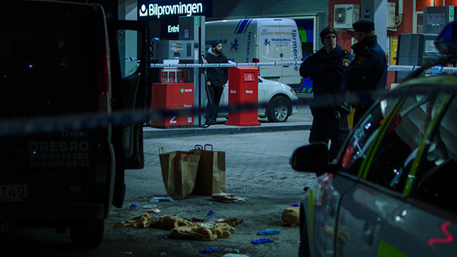 Två poliser håller vakt vid avspärrningen utanför bensinstationen. Foto: Nyheter Idag